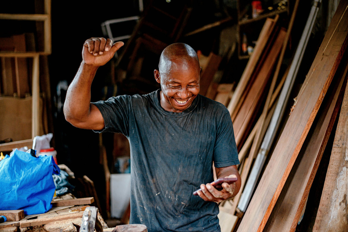 A furniture maker reading good news on his phone