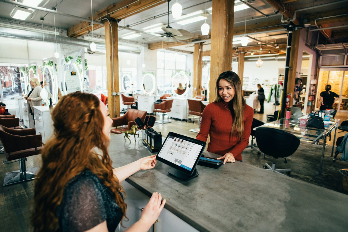 A salon owner taking a card payment at her counter
