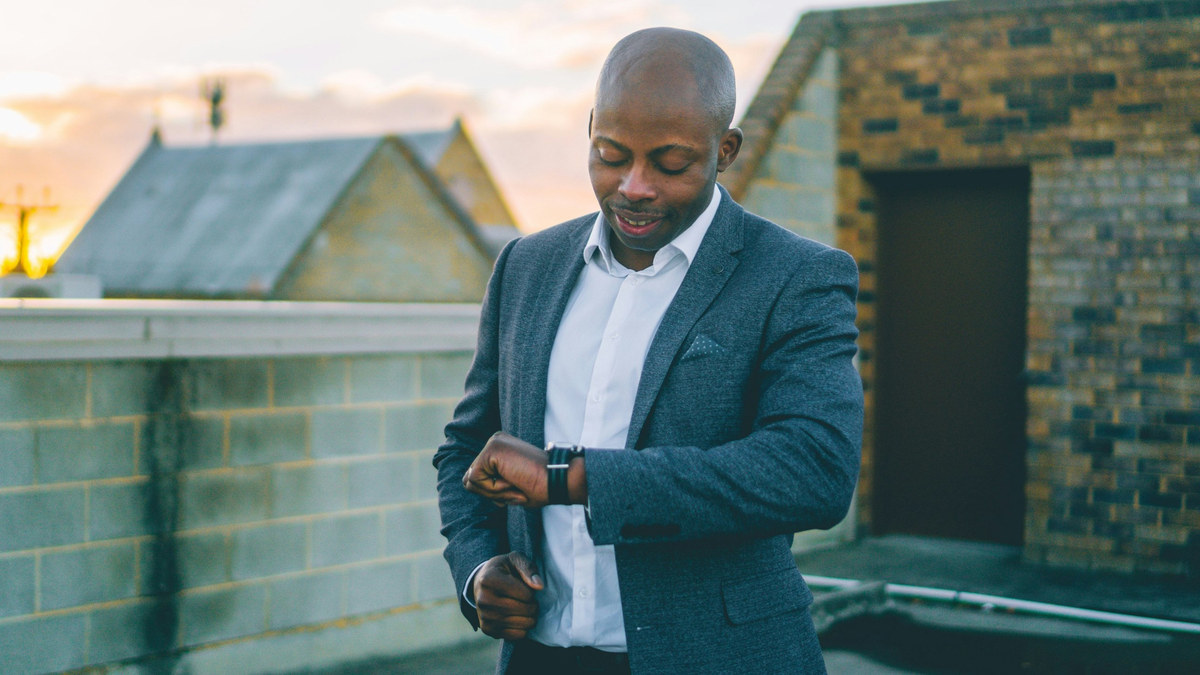 A business owner checking his watch on a rooftop at sunset